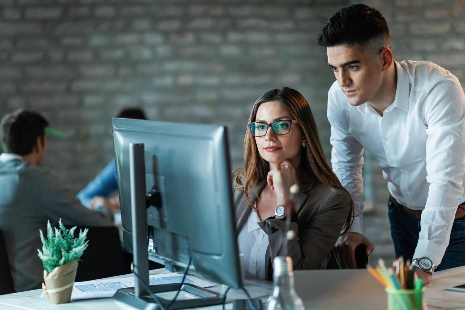 Two business colleagues reviewing data on a computer screen in an office environment