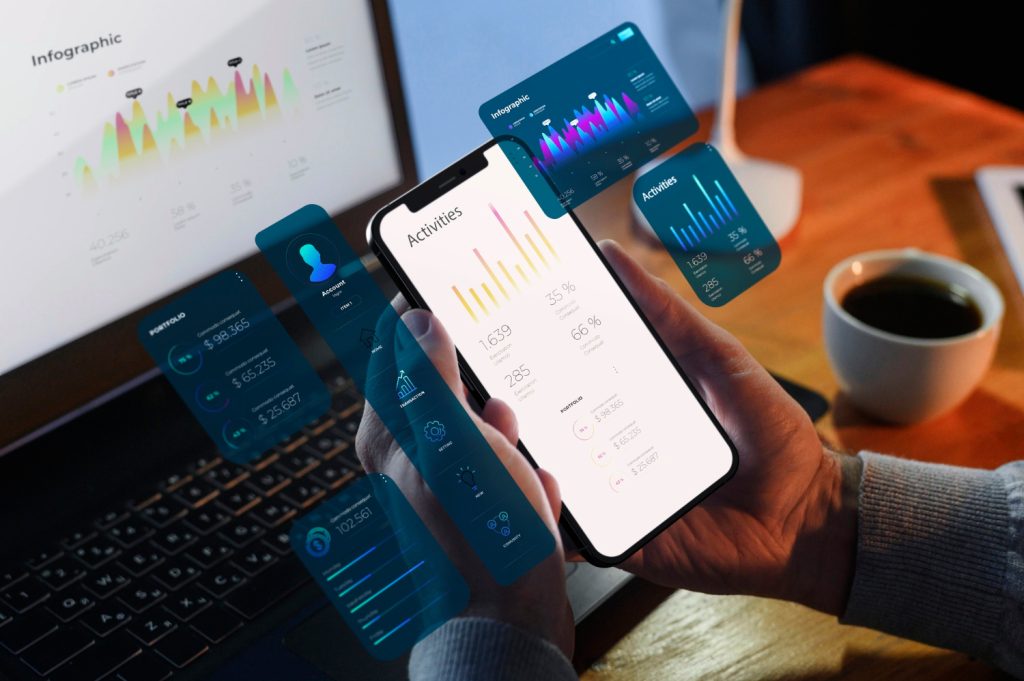 A person holds a smartphone displaying activity statistics, with digital charts and graphs overlaid, showcasing innovation by app developers Austin , next to a laptop and a cup of coffee on a desk.